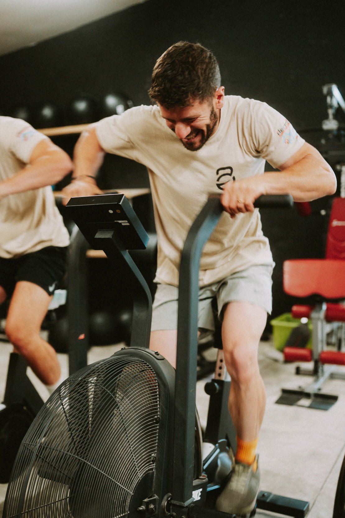 Athlète à l'effort sur un vélo à air (air bike) pendant un WOD à O'GYM