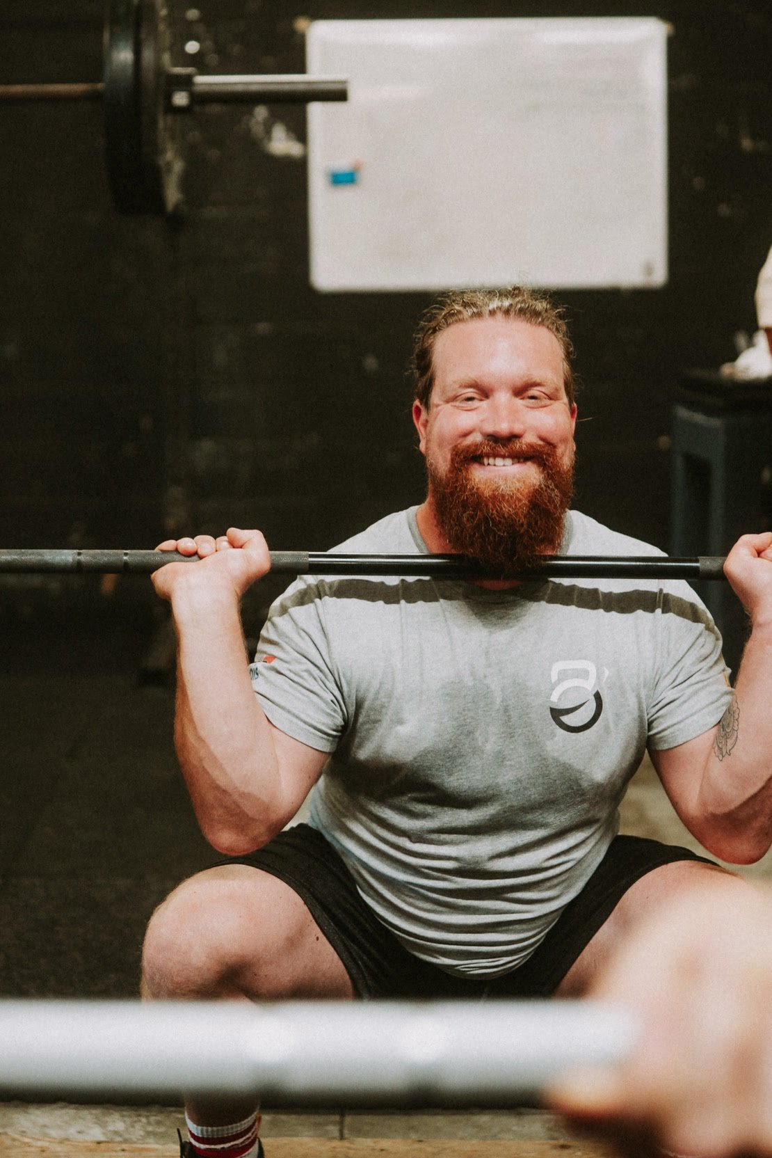 Sportif souriant en front squat avec la barre sur les épaules à O'GYM