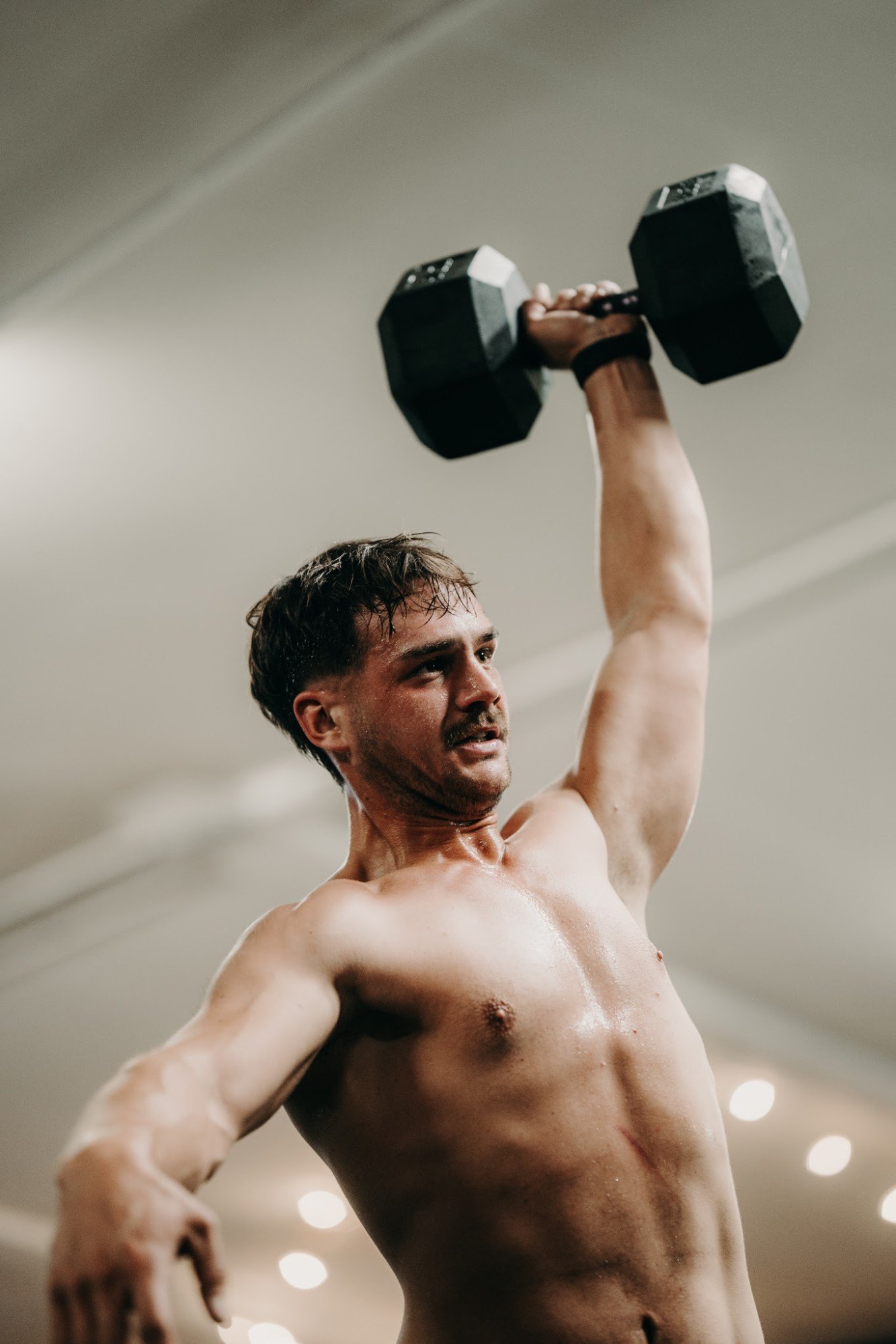 Athlète en développé d'haltère à une main pendant un WOD inspiré CrossFit à O'GYM Neufchâteau